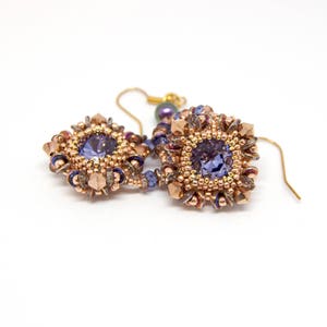 May include: A pair of dangle earrings with a square-shaped purple gemstone surrounded by gold and copper beads.