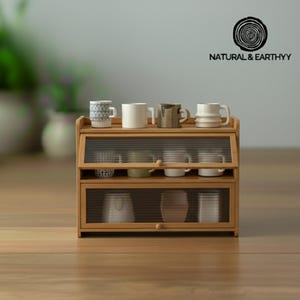 May include: A small, wooden cabinet with glass doors, displaying various ceramic mugs. The cabinet has two levels, with mugs of different colors and patterns. The text "NATURAL & EARTHYY" is visible on the top right.