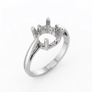 May include: A silver-toned metal ring setting featuring a four-prong head designed to hold a center stone. The gallery area displays an intricate, openwork filigree pattern, while the band remains smooth and polished, creating a clean look.