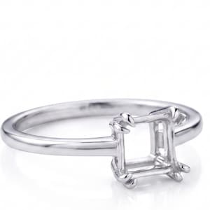 Può includere: Un anello d'argento con incastonatura quadrata, progettato per contenere una gemma. L'anello ha una fascia liscia e lucida e un'incastonatura dettagliata con griffe per fissare la pietra. L'anello è mostrato su sfondo bianco.