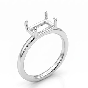 May include: A polished silver ring with a rectangular setting, designed to hold a gemstone. The ring features a smooth, rounded band and four prongs to secure the stone. The setting is elevated above the band.