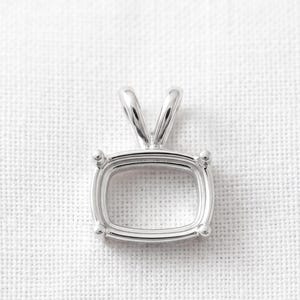 May include: A silver-toned metal pendant setting featuring a rectangular, cushion-shaped frame with rounded corners. The setting includes four small prongs at each corner to secure a gemstone and a V-shaped bail at the top for a necklace chain.