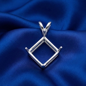 Può includere: Un supporto per ciondolo argentato con design quadrato, con quattro griffe per tenere una pietra preziosa. Il ciondolo ha un anello nella parte superiore per una catena ed è posto su uno sfondo di raso blu scuro.