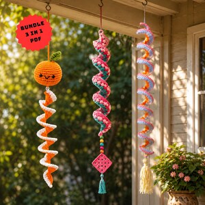 Könnte beinhalten: Drei hängende Häkelornamente bestehend aus einer lächelnden Orange mit grünem Blatt, einer pink-türkisen Spirale mit quadratischem Motiv und Perlen sowie einer pastellfarbenen Regenbogenspirale mit cremefarbener Quaste. Text BUNDLE 3 IN 1 PDF.