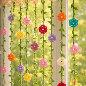 Könnte beinhalten: Ein handgefertigter Häkelvorhang mit floralem Design. Der Vorhang zeigt bunte Blumen in den Farbtönen Rosa, Gelb, Orange, Rot, Lila und Weiß, die an grünen Ranken aufgereiht sind. Die Oberseite hat eine grüne und beige Häkelborte.