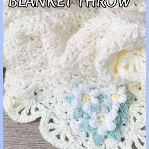 Beautiful lacy crochet blanket is laying tossed on a wooden surface. The blanket is crocheted with cream soft yarn and is airy and textured with the scalloped border giving it a vintage cottagecore vibe. There is a crochet flower applique in the corner of the blanket - three puffy white  daisies framed with pale green leaves. The lettering says: "Vintahe Lace Blanket Throw", "Crochet Pattern By JTEasyCrochet" meaningthat JTEasyCrochet has the best and easy crochet patterns.