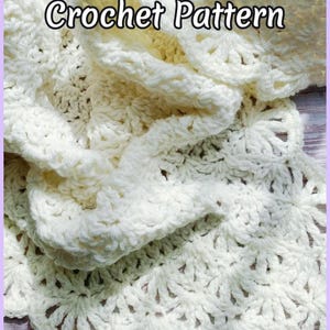 Beautiful lacy crochet blanket is laying tossed on a wooden surface. The blanket is crocheted with cream soft yarn and is airy and textured with the scalloped border giving it a vintage cottagecore vibe. There is a crochet flower applique in the corner of the blanket - three puffy white  daisies framed with pale green leaves. The lettering says: "Throw Blanket Crochet Pattern", "JTEasyCrochet" meaning that JTEasyCrochet has the best crochet patterns, easy and beautiful.