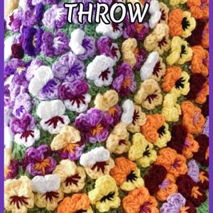 : Beautiful round crochet blanket or crochet rug is hanging from a display. The blanket is made of colorful pansy flowers arranged in circular pattern and the fringe og the blanket is made of green pansy leaves. The lettering says: "Pansy Blanket Throw", "Crochet Pattern By JTEasyCrochet" meaning that JTEasyCrochet has the best crochet patterns and fun crochet ideas.