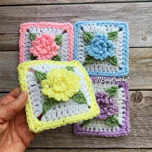 May include: Four crochet squares with floral designs in various colours. Each square has a different coloured flower: pink, blue, yellow, and purple. The squares have white centres and are bordered in matching colours. The text "JTEasyCrochet" is visible on one square.