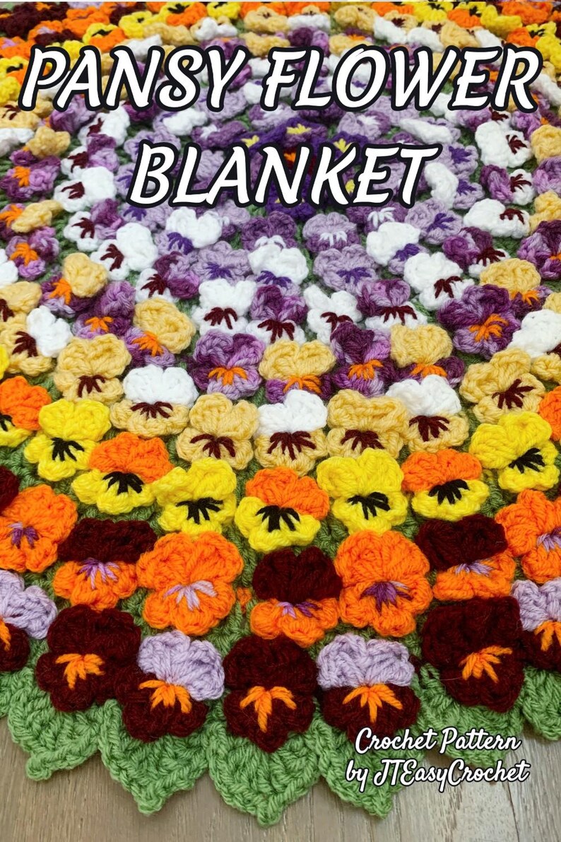 A colorful crochet blanket featuring a pattern of pansy flowers in shades of orange, yellow, purple, and white. The blanket has a green scalloped edge and text that reads "PANSY FLOWER BLANKET" and "Crochet Pattern by JTEasyCrochet". JTEasyCrochet has the best crochet patterns.