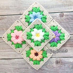 May include: Five crocheted squares arranged in a diamond pattern. Each square features a central flower in shades of pink, white, blue, peach, and purple, surrounded by green leaves. The squares are set against a neutral background, with the text "JTEasyCrochet" visible.