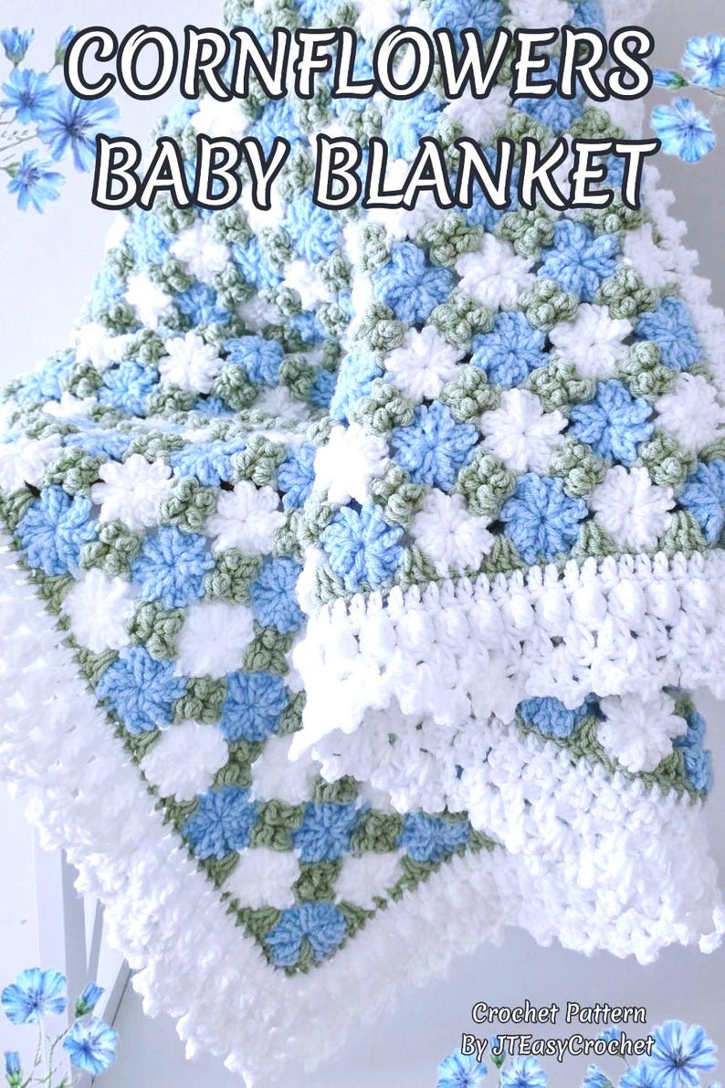 Lavishly beautiful crochet floral blanket made of cornflower motifs is hanging from a display. The blanket resembles a field of white and blue cornflowers framed with a beautiful lace edging.  The lettering says "Cornflowers Baby Blanket", "Crochet Pattern By JTEasyCrochet" meaning that JTEasyCrochet has the best crochet patterns for flower baby blankets, throws and afghans.