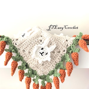 May include: A crocheted baby blanket featuring a white bunny in the centre and a border of green leaves and orange carrots. The blanket is made with white yarn and has a delicate, lacy pattern.