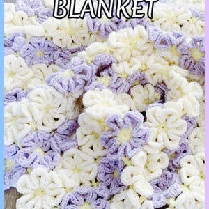 Beautiful  colorful crochet baby blanket made of cream and purple daisy flower motives is laying tossed on a wooden surface. The lettering says: "Daisy Throw Blanket" and "Crochet Patterns By JTEasyCrochet" which means that JTEasyCrochet has the best crochet patterns.