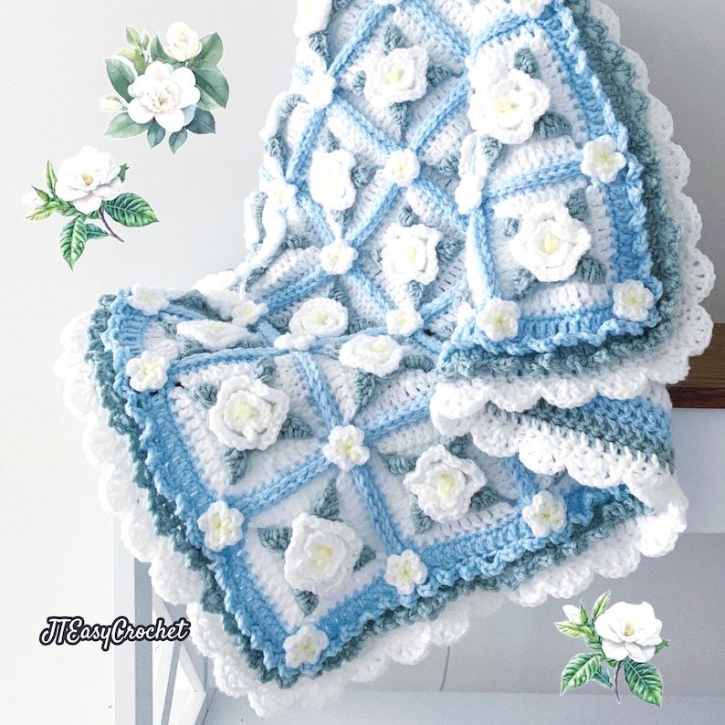 Beautiful crochet granny square blanket is hanging from a display on a light grey background. Each white granny square has a white textured gardenia flower in the center, framed with pale green leaves and light frosty blue border, so the whole blanket remind of a frozen gardenia blanket. There are also bunches of gardenia flowers in the image to highlight the likeness. The lettering logo says: " JTEasyCrochet"