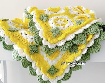 May include: A crocheted baby blanket in yellow, white, and green with a scalloped edge. The blanket is made with a granny square pattern and features a leafy border.