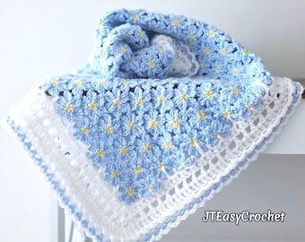 May include: A handmade crochet blanket featuring a repeating pattern of light blue flowers with yellow centers. The blanket is bordered by a wide white openwork crochet edge and includes the text JTEasyCrochet in the bottom right corner.