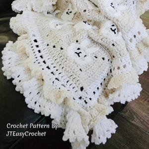 Beautiful Bunny  granny square blanket with fringed edging is laying on a dark leather couch. The blanket is cream with white bunnies on each square. The lettering says: “Crochet Pattern By JTEasyCrochet” meaning that JTEasyCrochet has the best crochet patterns and fun crochet ideas.