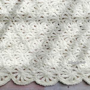May include: Cream-colored, handmade crochet blanket with a detailed floral pattern. The blanket has a scalloped edge and is made of soft yarn. The text "JTEasyCrochet" is visible in the lower right corner.