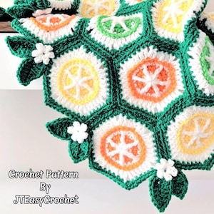 Puede incluir: Una manta de ganchillo hecha a mano con un vibrante diseño de frutas cítricas. La manta presenta patrones hexagonales con rodajas de limón, lima y naranja, delineadas en blanco y verde. Flores blancas y hojas verdes están unidas a la manta. El texto "Crochet Pattern By JTEasyCrochet" es visible.