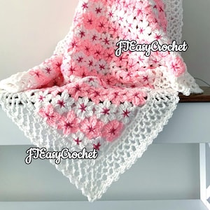 May include: A handmade crochet blanket featuring a floral pattern in shades of pink and white. The blanket has a delicate, openwork border and the text "JEasyCrochet" is visible. This cozy blanket is perfect for adding a touch of handmade charm to any space.