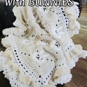 Beautiful Bunny  granny square blanket with fringed edging is laying on a dark leather couch. The blanket is cream with white bunnies on each square. The lettering says: “Baby Blanket With Bunnies”, “Crochet Pattern By JTEasyCrochet” meaning that JTEasyCrochet has the best crochet patterns and fun crochet ideas.