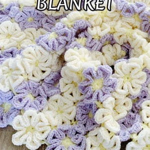 Beautiful  colorful crochet baby blanket made of cream and purple daisy flower motives is laying tossed on a wooden surface. The lettering says: "Daisy Throw Blanket", "Crochet Pattern by JTEasyCrochet" which means that JTEasyCrochet has the best crochet patterns.