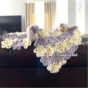 A crocheted blanket with a flower pattern in shades of purple and yellow. The blanket is folded and draped over a brown couch. The text "JTEasyCrochet" is visible in the image.