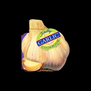 May include: A garlic bulb with a clove and a tag that reads "Totally Garlic Cookbook." The bulb is off-white with brown and yellow accents. The tag is green, yellow, and blue. The cookbook is likely about garlic recipes.