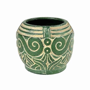 May include: A green ceramic vase with a textured surface and cream-colored accents. The vase features a rounded shape with a wide opening and is adorned with a repeating pattern of swirls and geometric shapes. The vase measures approximately 6 inches in height.