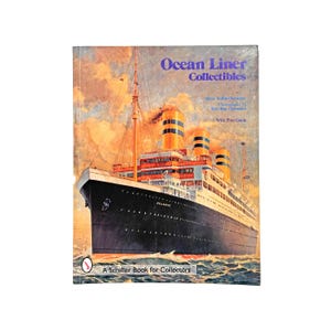 May include: A vintage book titled "Ocean Liner Collectibles" featuring a detailed illustration of a large ocean liner. The cover has a blue title and a picture of the ship on the water. The book is a Schiffer Book for Collectors.