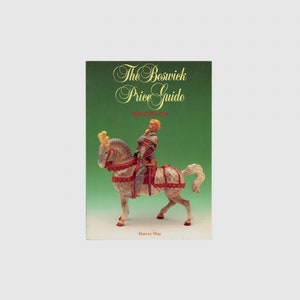 May include: A book titled "The Beswick Price Guide 1993 Edition" with a green cover. The cover features a figurine of a knight on a horse. The horse is gray and white with red and gold accents. The knight is wearing silver armor.