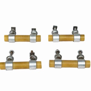 May include: Four vintage cabinet pulls. Each pull features a cylindrical, light brown handle held by two silver-toned metal bands. The bands are connected to mounting hardware with screws and nuts. The pulls are set against a white background.