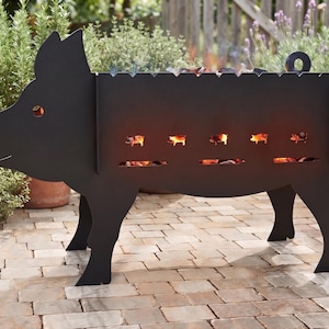 May include: A black metal fire pit shaped like a pig with a curly tail. The side of the pig features cutouts of smaller pigs and horizontal slits that reveal glowing orange embers and flames from within the fire box, creating a warm light.