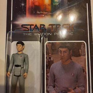 May include: A vintage Star Trek: The Motion Picture action figure of Commander Sonak, in original packaging. The figure is grey with a red emblem. The packaging features images of the characters and the film's title.