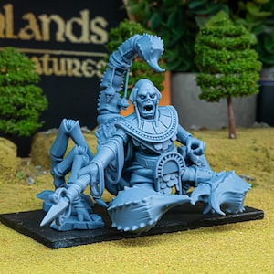 Op de afbeelding: Lichtblauwe miniatuur van een op een schorpioen lijkend wezen met een menselijk torso, zittend op een troon. De figuur heeft een open mond en is omgeven door gedetailleerde schorpioenklauwen en -staart. De miniatuur staat op een zwarte basis.