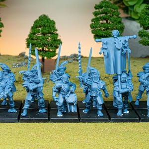 Op de afbeelding: Een verzameling blauwe miniatuurfiguren van soldaten, elk met zwaarden en andere wapens. De figuren staan op zwarte bases, met een achtergrond van miniatuurbomen en een grasachtig oppervlak.