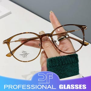 Puede incluir: Gafas de montura redonda en color marrón claro. Las gafas tienen una montura metálica fina y lentes transparentes. También se ve el texto "PROFESSIONAL GLASSES".
