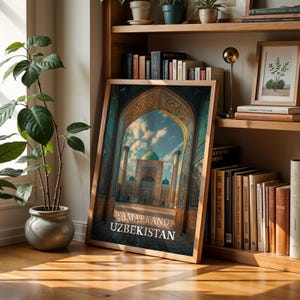 May include: A framed print featuring a detailed architectural view of Samarkand, Uzbekistan, with ornate archways and a blue-domed structure under a cloudy sky. The print is in a wooden frame, leaning against a wall near a potted plant and a bookshelf.