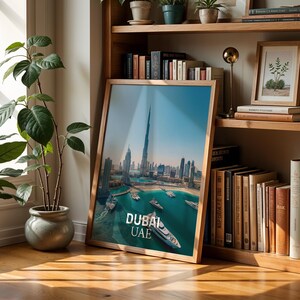 May include: A framed print featuring a scenic view of Dubai, UAE, with the Burj Khalifa dominating the skyline. The image showcases a turquoise bay with boats, and the text "DUBAI UAE" is prominently displayed. The frame is made of light-colored wood.