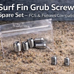 May include: A clear plastic bag containing several silver-colored surf fin grub screws. The text "Surf Fin Grub Screws Spare Set - FCS & Futures Compatible" is displayed at the top of the image. The screws are designed for surfboards.