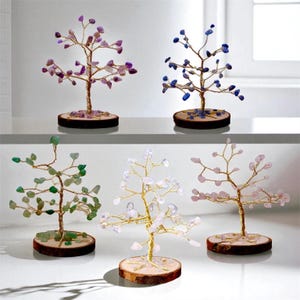 May include: Five decorative gemstone trees with wire branches and wooden bases. The trees feature amethyst, blue, green, clear, and pink gemstones. The trees are arranged on a white shelf.