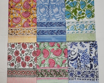 May include: A collection of colorful, patterned fabric pieces. The designs include floral and geometric patterns in various colors such as yellow, blue, green, pink, and white. The fabrics appear to be cotton or a similar material, suitable for home decor or crafting.