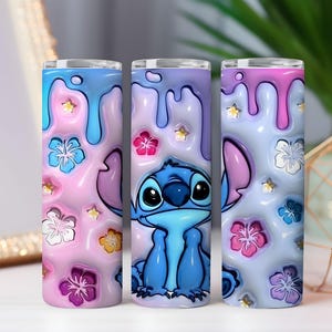 May include: Three 20 oz. insulated tumblers with a cartoon Stitch design. The tumblers feature a pink, blue, and purple color scheme with floral and star accents. The design includes a 3D effect with dripping paint.