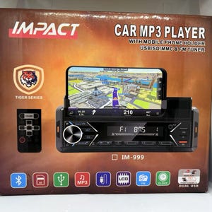 Puede incluir: Un reproductor MP3 para coche con soporte para teléfono móvil, USB, SD, MMC y sintonizador FM. La caja presenta el logotipo "IMPACT", un emblema de tigre y el texto "TIGER SERIES". El reproductor muestra un mapa en un teléfono.