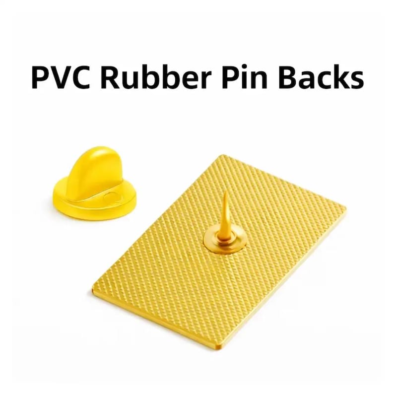 Pu&ograve; includere: Primo piano di retro in gomma PVC per spille. L'immagine mostra un retro spilla rettangolare color oro con una superficie strutturata e un perno. &Egrave; visibile anche una frizione in gomma gialla.
