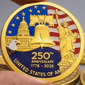Pu&ograve; includere: Una moneta commemorativa dorata che celebra il 250&deg; anniversario degli Stati Uniti d'America. La moneta presenta il Campidoglio, la Liberty Bell, la Statua della Libert&agrave; e un'aquila. Il testo recita "250th Anniversary 1776-2026 United States of America."