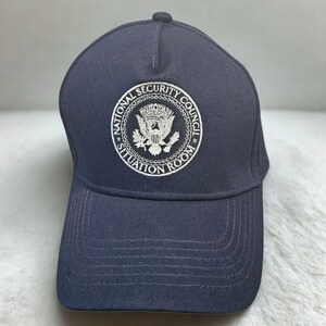 May include: Navy blue baseball cap featuring the embroidered emblem of the National Security Council, with the text "National Security Council Situation Room" in a circular design. The cap has a curved brim and a top button.