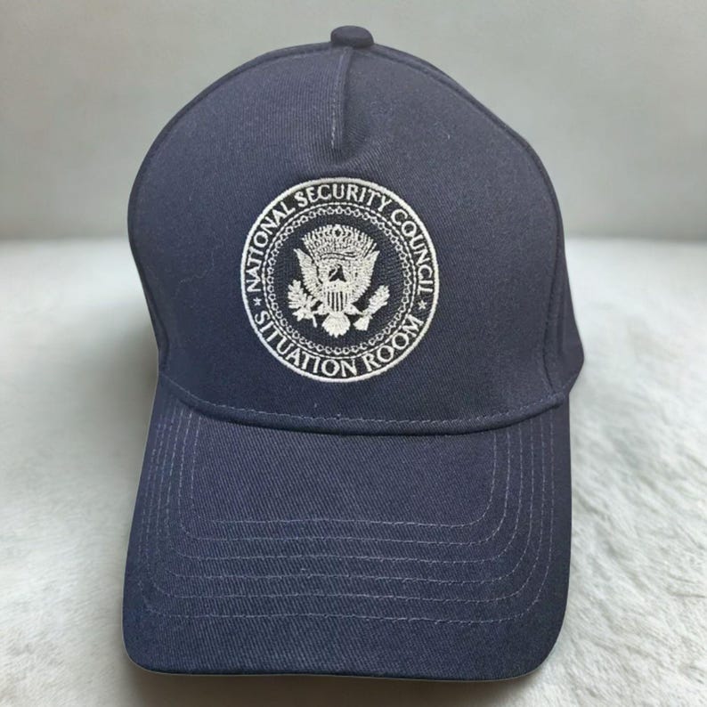 May include: Navy blue baseball cap featuring the embroidered emblem of the National Security Council, with the text "National Security Council Situation Room" in a circular design. The cap has a curved brim and a top button.
