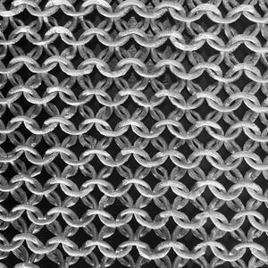 May include: Close-up of a chainmail texture. The image shows a dense pattern of interlocking metal rings in shades of gray and silver against a dark background. The chainmail appears to be made of small, circular links, creating a flexible, mesh-like structure.